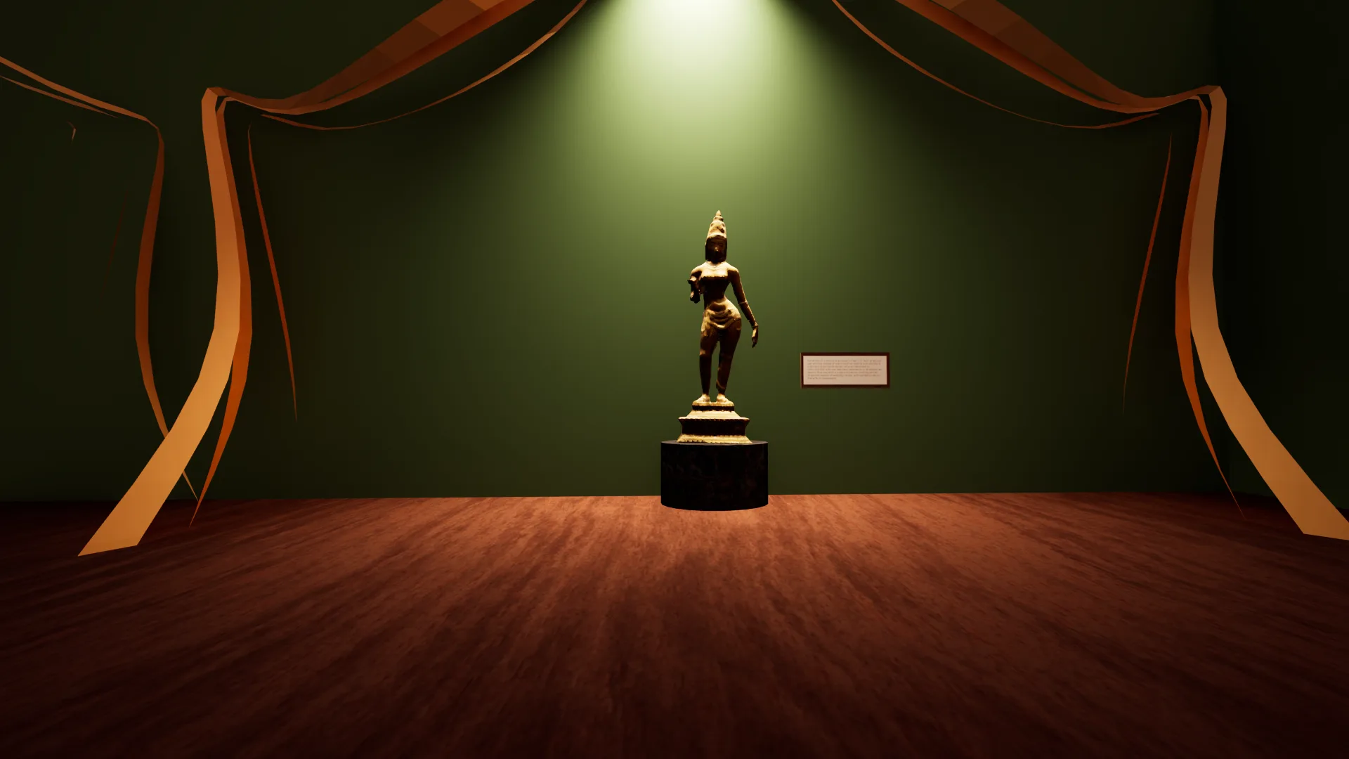 Bronze standing figure on a black plinth under a spotlight against a green wall framed by copper drapes, with a wall label beside it